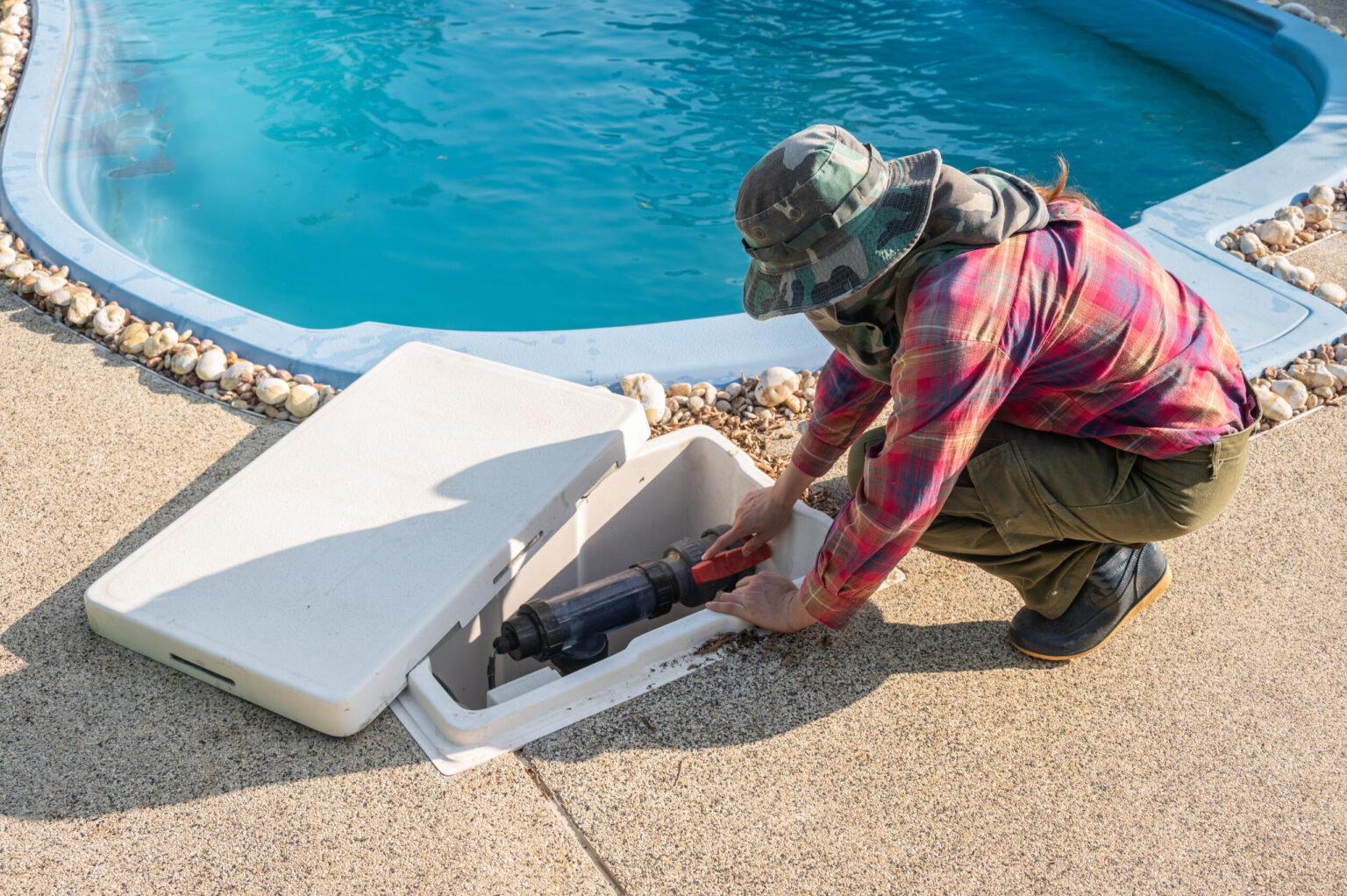 Technicien en intervention sur une pompe de piscine en local technique.