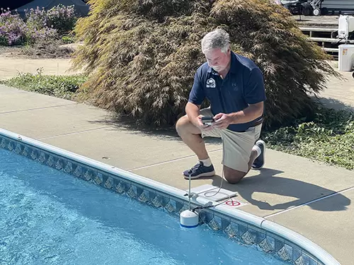 Technicien équipé d'un détecteur électroacoustique pour recherche de fuite piscine.